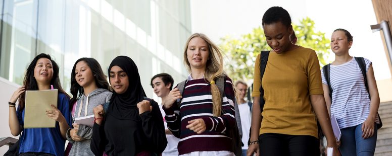 Grupo diverso de estudiantes caminando en la preparatoria en Estados Unidos